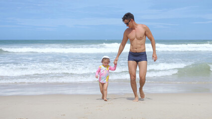 Athletic man runs out of water leading little girl in panama