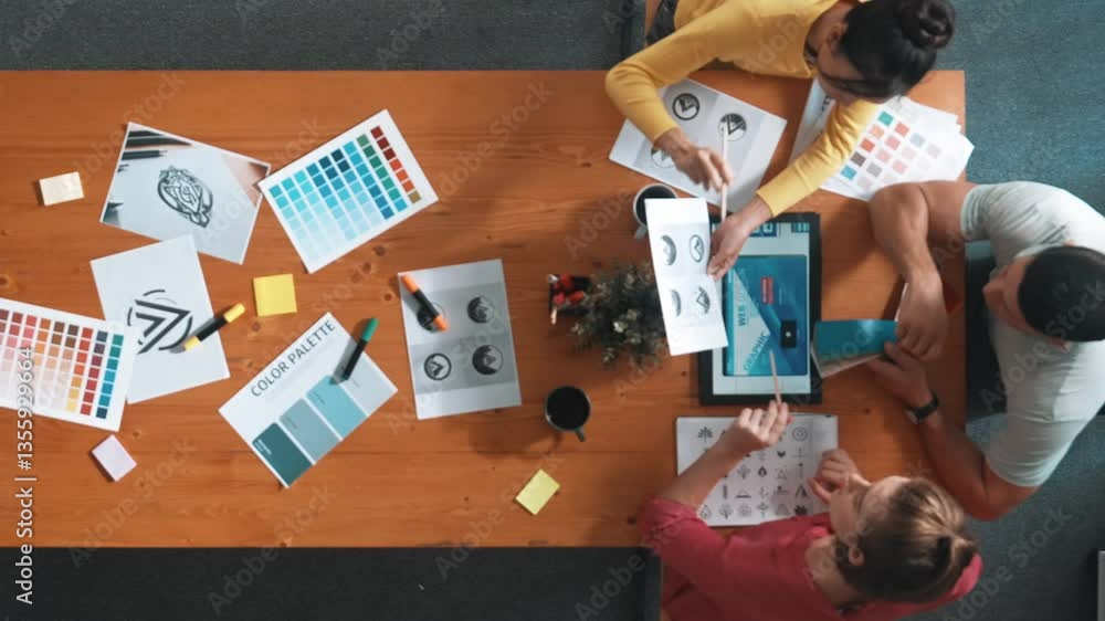 Poster top down aerial view of designer looking at tablet while project manager choosing color palettes. to