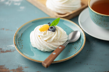 Delicious mini Pavlova meringue cake with whipped cream and fresh fruits.
