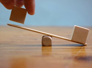 hands holding a wooden block on a seesaw to balance. concept of stability and business. copy space for text