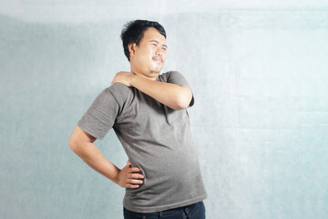 an Indonesian is posing with a cramp in his body on a plain background