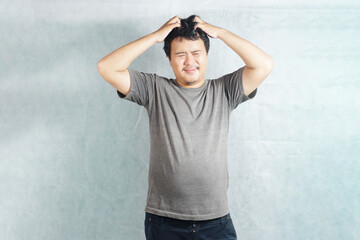 an Indonesian posing scratching his head on plain background 