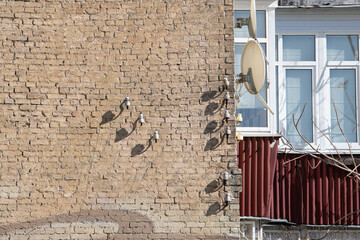 A well-worn brick wall displays various textures, with shadows cast by mounted fixtures. A nearby...
