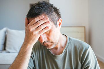 Fototapeta premium Headshot portrait of sad and depressed man in living room, alone at home
