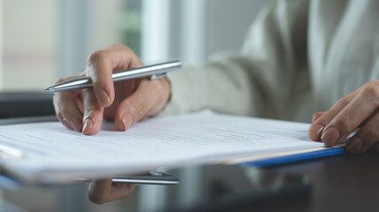 Business woman reading before signing document. Close up of woman hand with a pen signing business...