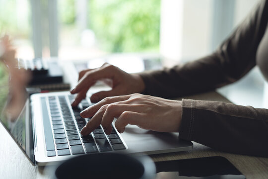 Fototapeta Business woman in casual dress working on laptop computer at home office. Close up, woman online working, surfing the internet, typing on laptop on office table, remote work, side view