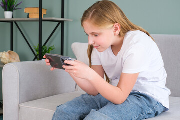 A stooped child uses a mobile phone. Violation of posture