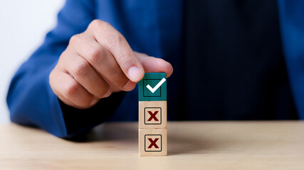 Businessman select blue correct sign mark between Red Cross mark which print screen on wooden for approve and reject business project proposal concept.