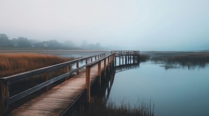 Obraz premium Wooden walkway leading into the fog over a calm body of water