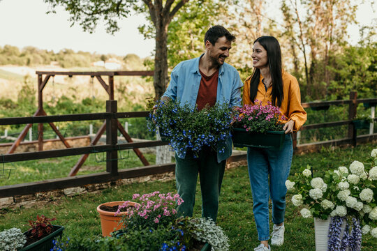 Couple carrying flowers in garden during spring enjoying gardening