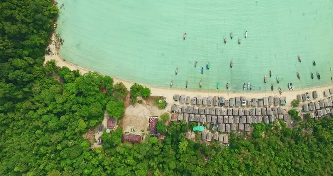  A stunning aerial view of a tropical beach village with rows of small huts along the coastline, Traditional fishing boats are anchored in the turquoise waters at Morgan village. white sandy beach.