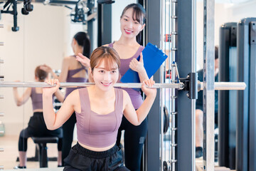 ジムで女性コーチのパーソナルトレーニングを受ける女性