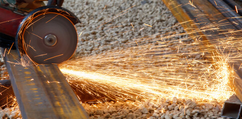 A piece of machinery is cutting through a metal bar