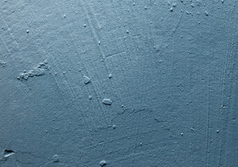 A blue wall with a rough texture and a few spots