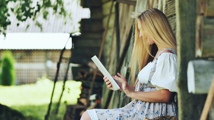 Blonde woman wearing traditional attire working on tablet near weathered wooden wall, merging...