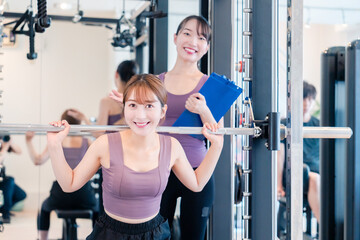 Naklejka premium ジムで女性コーチのパーソナルトレーニングを受ける女性