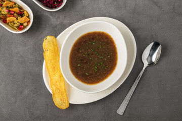 Steaming hot French onion soup served in a white bowl with golden toasted bread