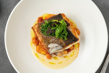 Crispy-skinned pan-seared fish fillet with chickpeas, creamy sauce, and fresh greens