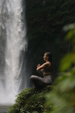 Woman practising yoga in front of waterfall on the island of Bali
