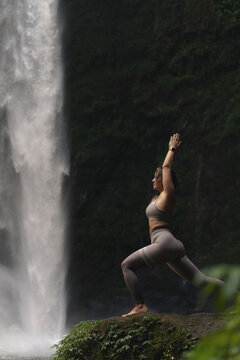 Woman practising yoga in front of waterfall on the island of Bali