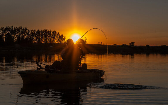 Man catching big fish at sunset