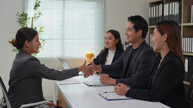 Asian businesswoman shaking hands with two human resource managers in the office after finishing up a job interview and being hired for the position