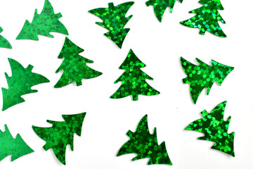 Holiday decorations shiny green Christmas trees lie chaotically on a white background.