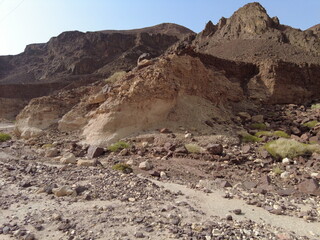 Desert landscape with rugged mountains and rocky terrain captured in bright sunlight during the day