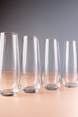 minimalistic arrangement of four empty clear glasses on pale orange surface against soft grey background creating transparent and reflective visual aesthetic, glass, presentation, arrangement, clean