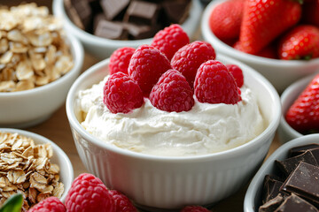 Close-up of yogurt with raspberries in a white bowl, surrounded by oats, strawberries, and chocolate pieces.  Showcases a healthy and delicious breakfast or dessert concept