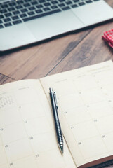 Calendar Planner book to plan reminder for daily appointment timetable, appointment, organization, and meeting agenda for job on wooden desk and working from home-vertical image.