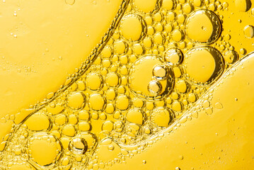 Beautiful macro photo of water droplets in oil with a yellow background. Abstract art