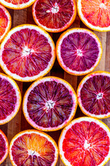 Red blood halved oranges close up on a wood background. Top view. Flat lay of fresh orange citrus...