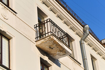 Old apartment balcony with cracked concrete and corroded metal railing, structural damage, neglect,...