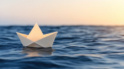 Obraz premium A paper boat floats gently on calm water under a serene sunset.