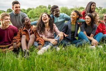 Diverse young friends laughing together in park enjoying outdoor moment