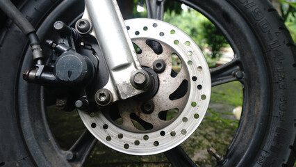 Obraz premium Motorcycle disc brake of front wheel and others details of brake caliper, rotor, rim, tire, and suspension