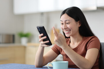 Fototapeta premium Happy asian woman crossing fingers checking smart phone