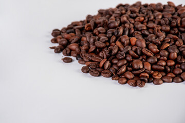 Pile roasted coffee beans isolated on a white background.