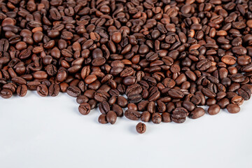 Pile roasted coffee beans isolated on a white background.