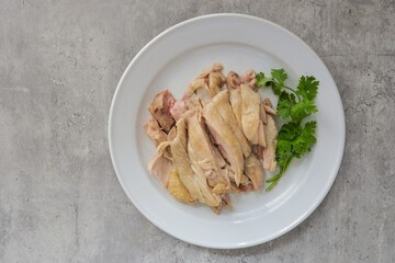 Boiled chicken in white plate on grey cememt background,hainanese chicken
