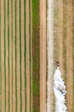 Aerial view of a cultivated field with lime application creating a white cloud