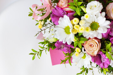 A vibrant bouquet of pink, white, and purple flowers, beautifully arranged in a pink box, perfect for a special occasion