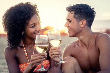 Young couple toasting at sunset on beach enjoying romantic summer moment