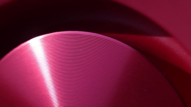 A vibrating red speaker with semicircular lines and a sun glare falling to the left in closeup