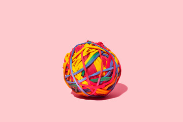Colorful ball of elastic bands on a pink background representing union and creativity