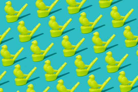Yellow plastic bird-shaped whistles arranged in a pattern on a blue background