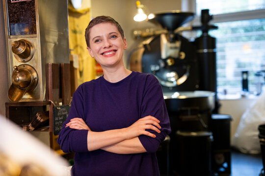 Confident businesswoman in a roastery smiling with arms crossed