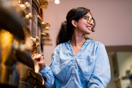 Young woman in a roastery smiling confidently packaging coffee beans