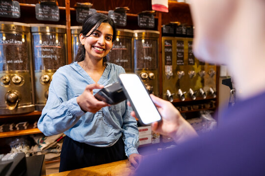 Salesperson in a roastery assisting a customer with a contactless payment
